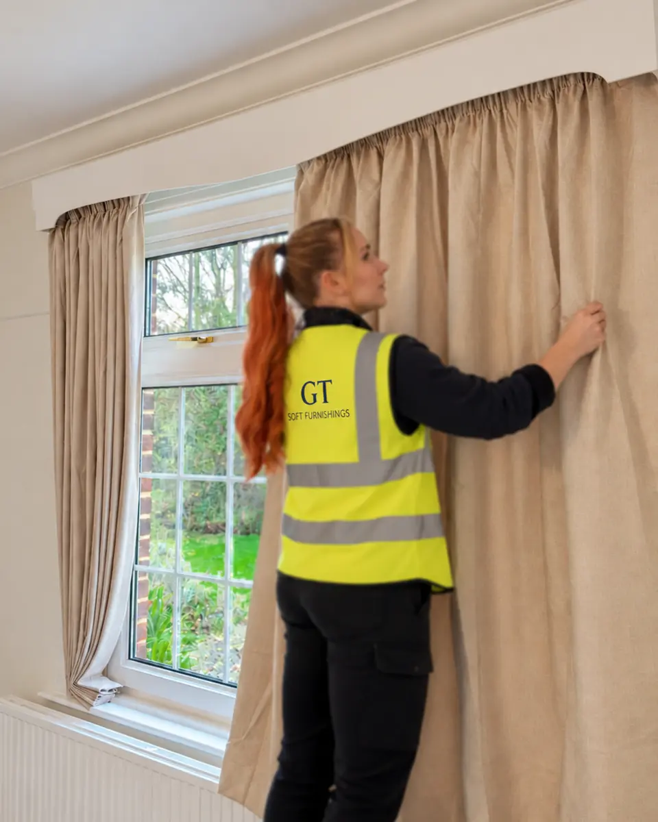 Beautifully dressed pencil-pleat curtain, with a GT fitter adjusting the matching curtain behind it